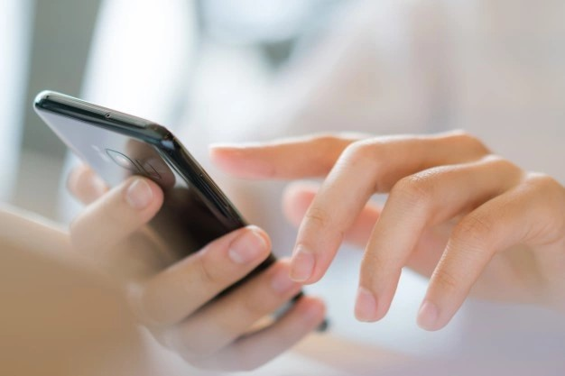 Osoba w ręku trzymająca telefon komórkowy