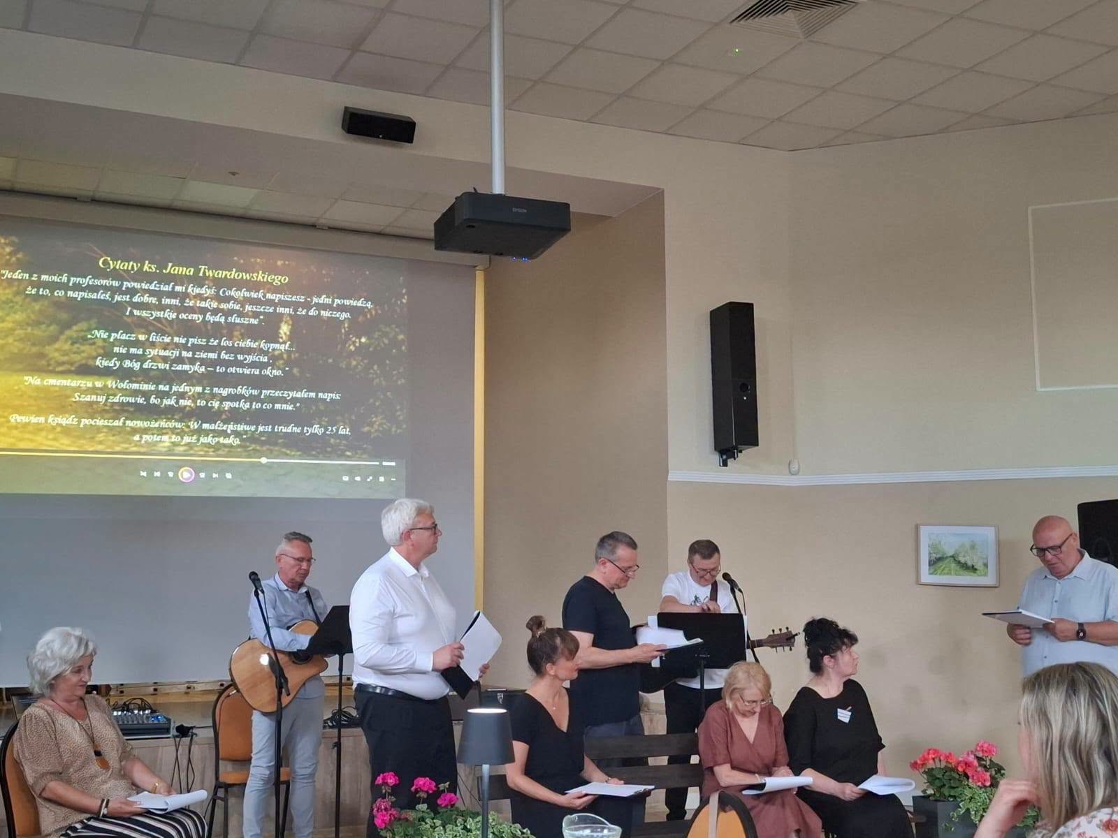 Uczestnicy salonu poezji, czytający i grający na instrumentach muzycznych