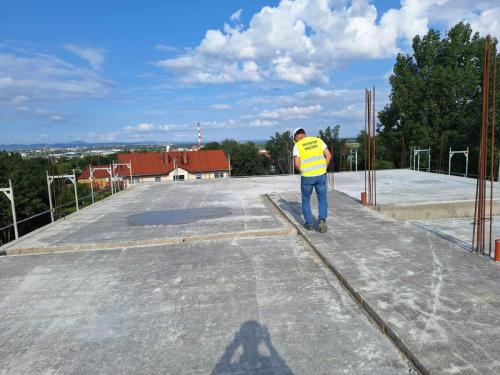 Budowa budynku komunalnego w Pszennie. Na jednym z pięter męzyczyzna w kamizelce odblaskowej z napisem inspektor nadzoru